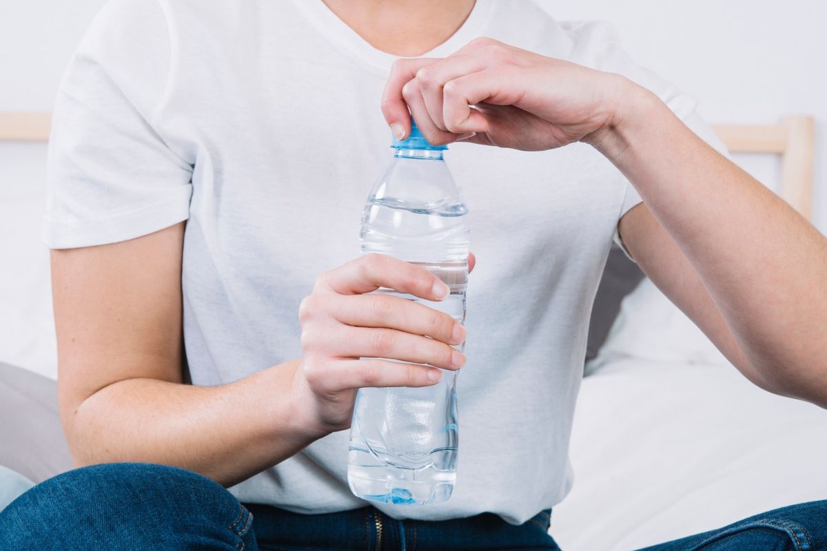 Seorang wanita membuka tutup botol air mineral