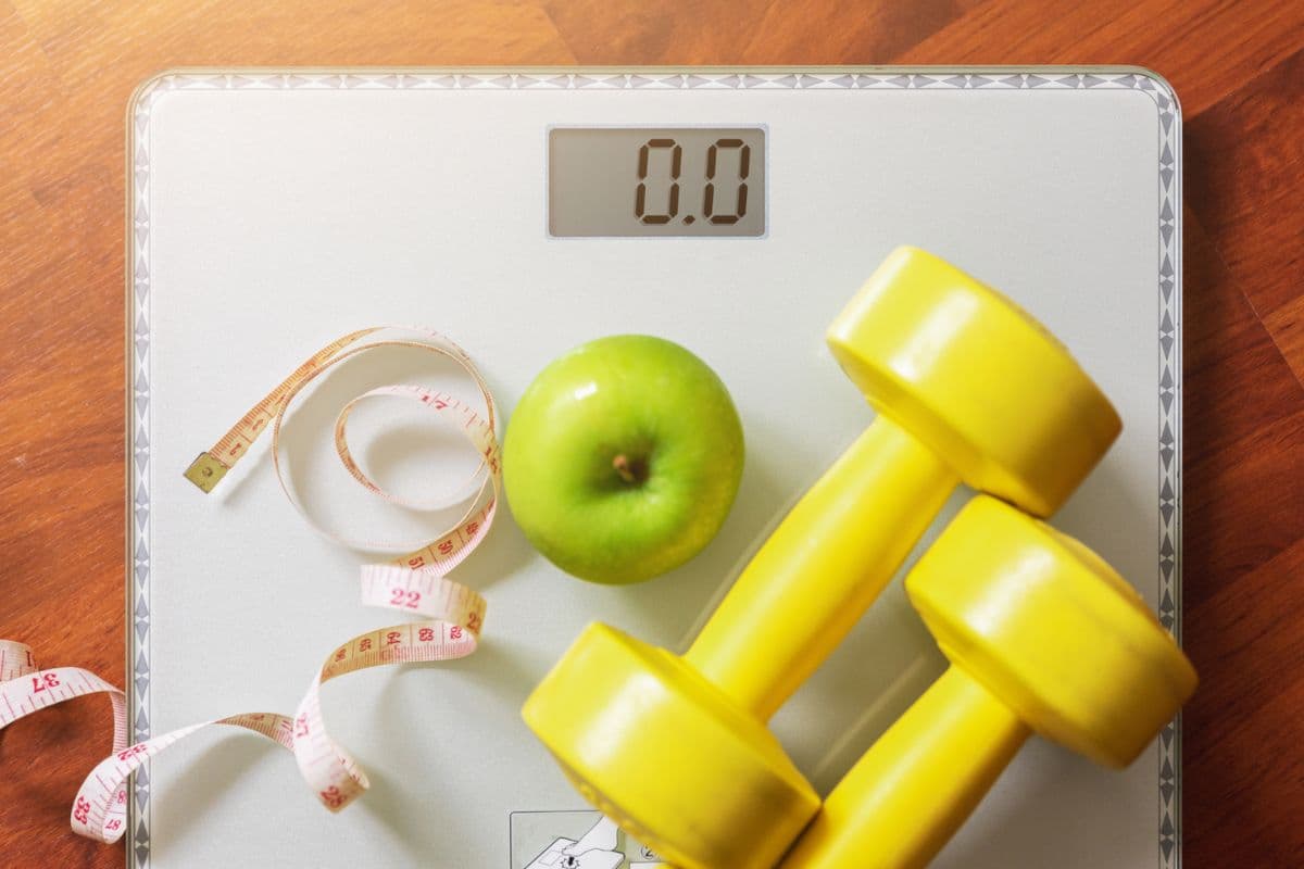 Timbangan badan, barbel, pita pengukur, dan apel