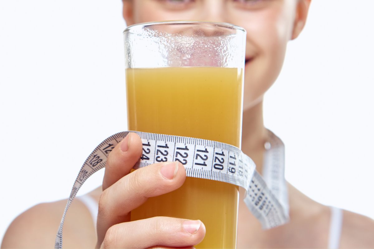 Seorang wanita sedang memegang gelas berisi minuman berwarna teh