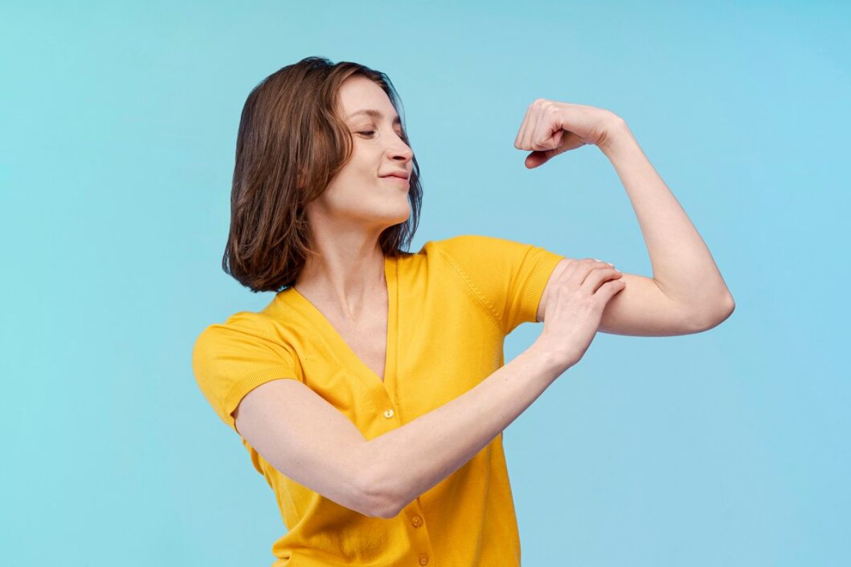 Perempuan berbaju kuning menunjukkan bicep