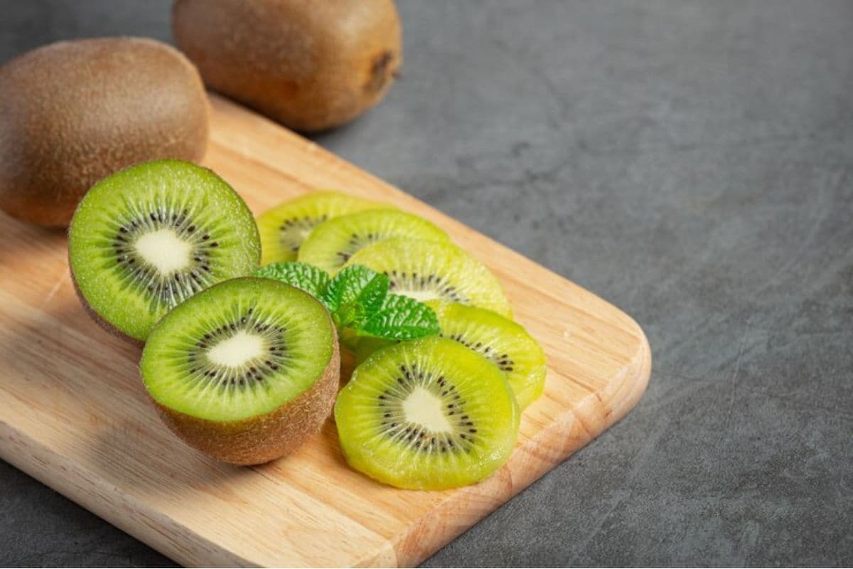 Buah kiwi yang sudah diiris, diletakkan di atas talenan kayu