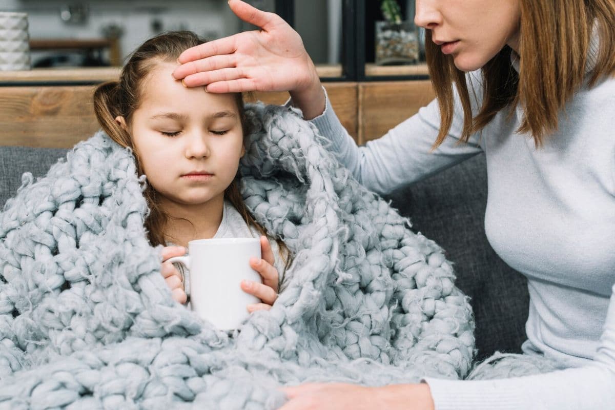 Anak demam yang memegang secangkir minuman