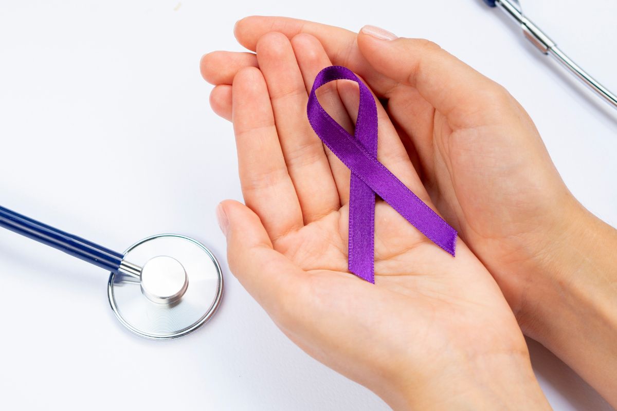 orang yang memegang pita ungu lambang kanker pankreas