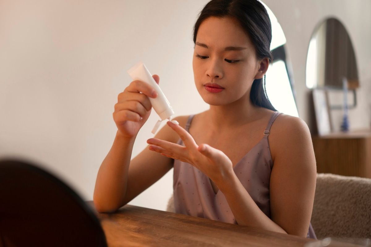 Seorang wanita mengeluarkan krim dari wadah ke jari