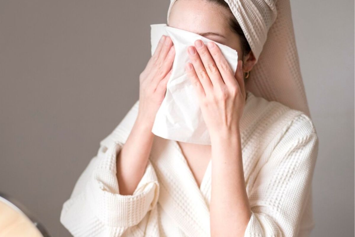 Seorang wanita sedang mengompres wajah dengan kain hangat