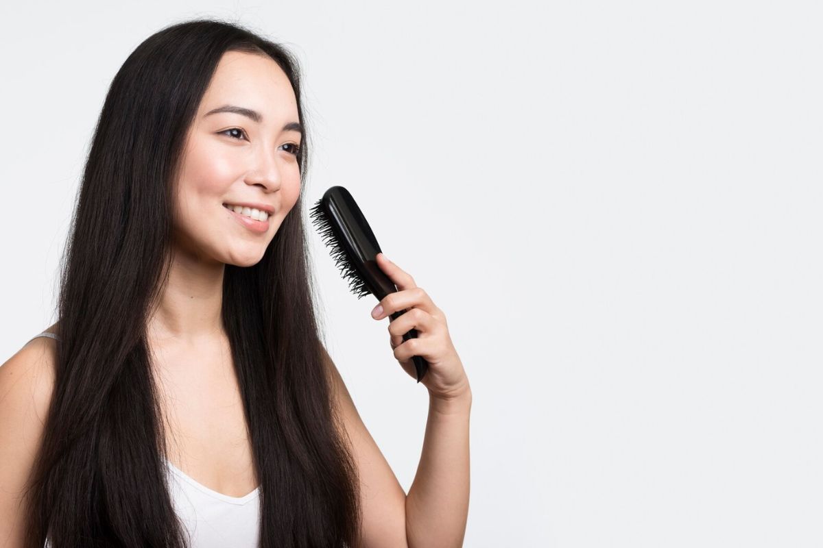 Wanita dengan rambut yang lebat dan panjang sedang memegang sisir