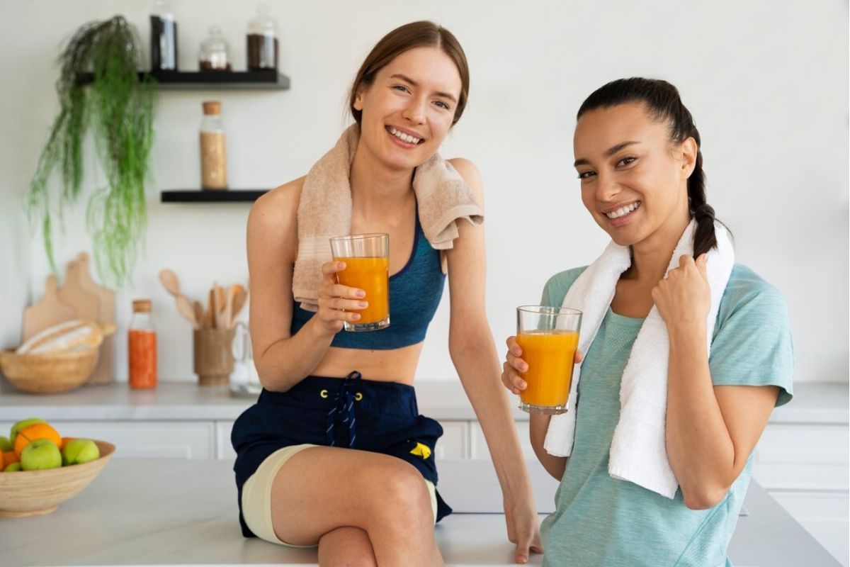 Dua orang perempuan di dapur memegang segelas jus