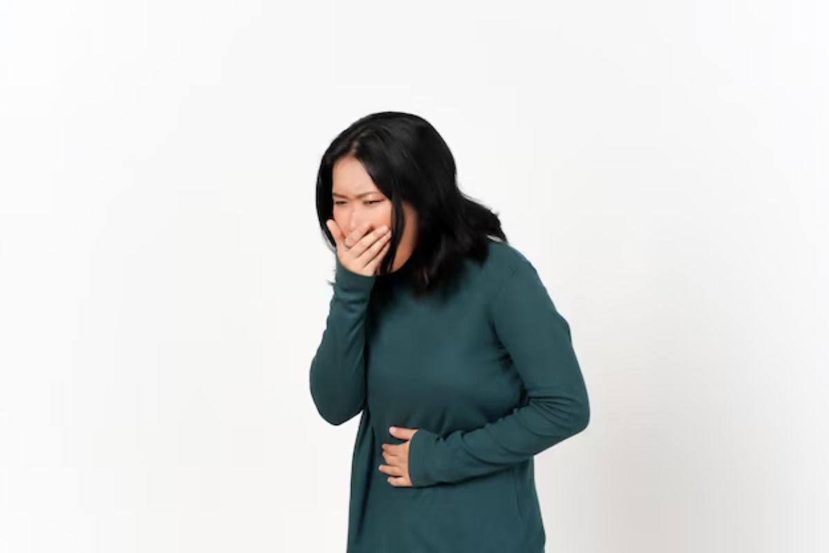 Seorang perempuan muda menunjukkan gestur mual sambil memegang perut