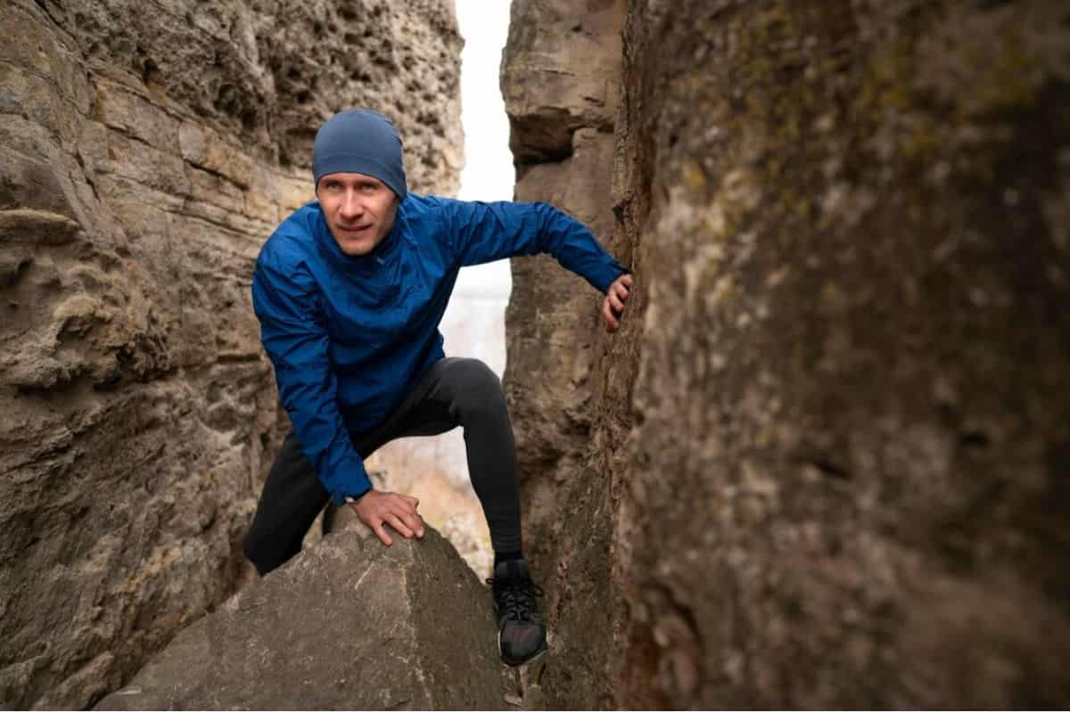 Laki-laki berbaju biru memanjat tebing