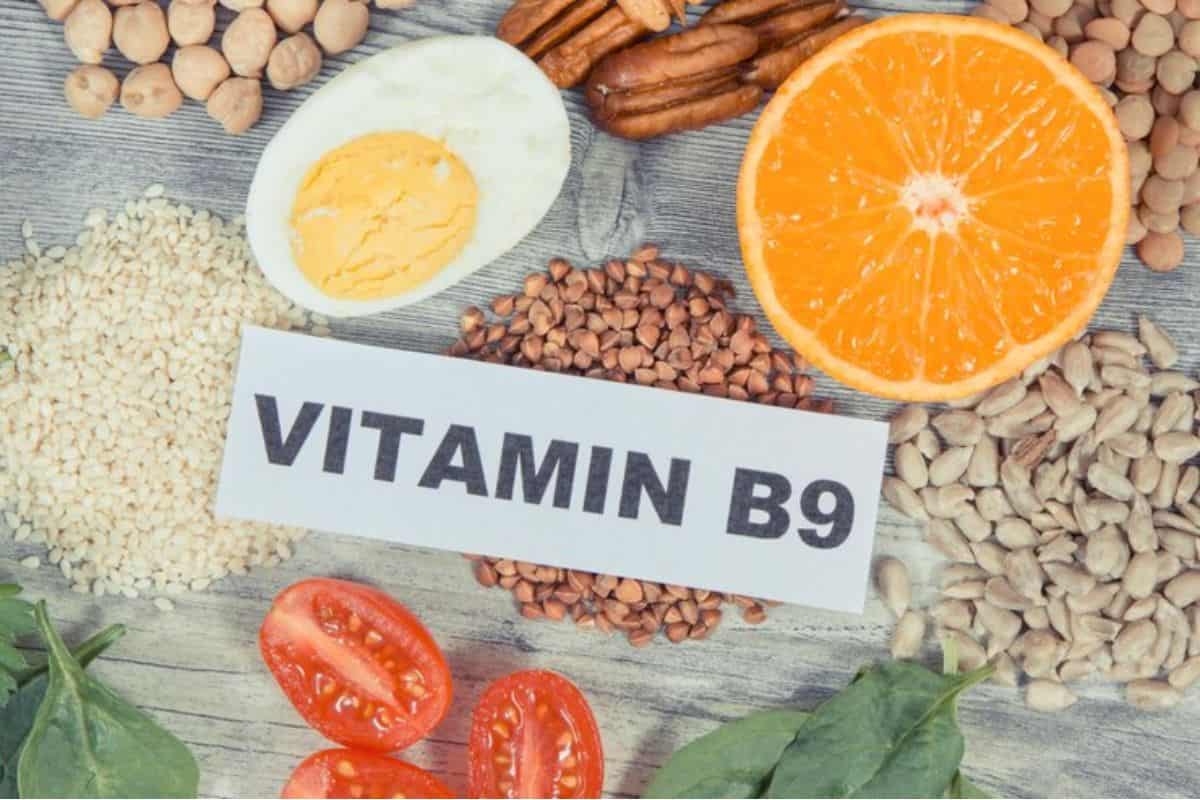 Berbagai makanan sumber vitamin B9 dan kertas bertuliskan 